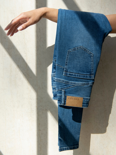LOVALL Denim Jeans folded over a woman's arm.